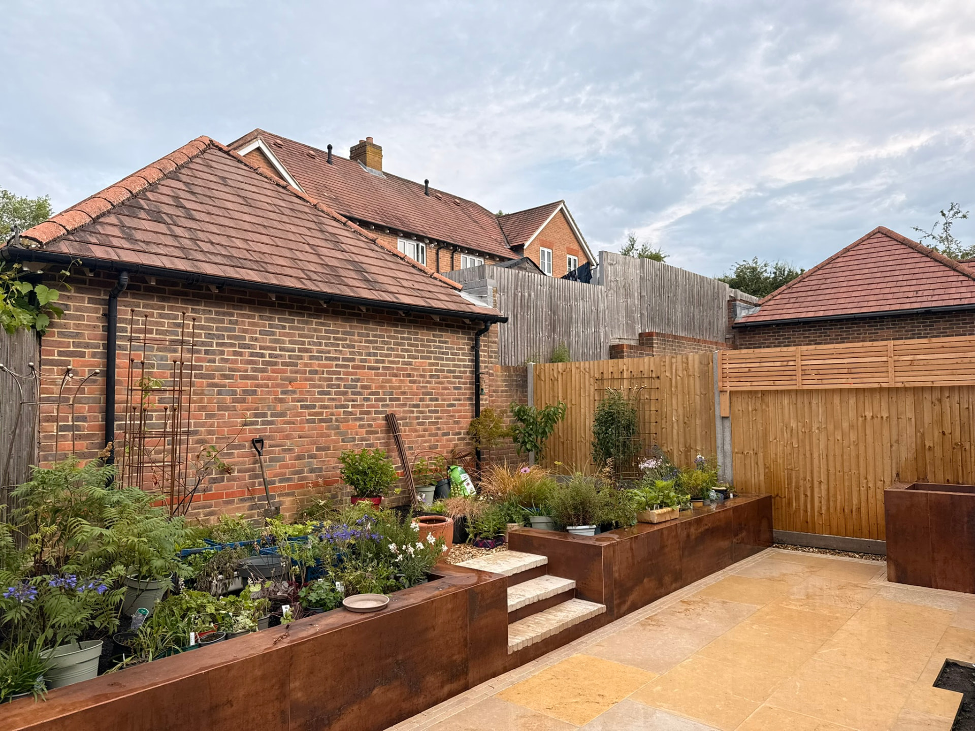 Finished Taurus Home and Garden landscaping project with a natural stone patio, raised corten steel planters and a new garden boundary